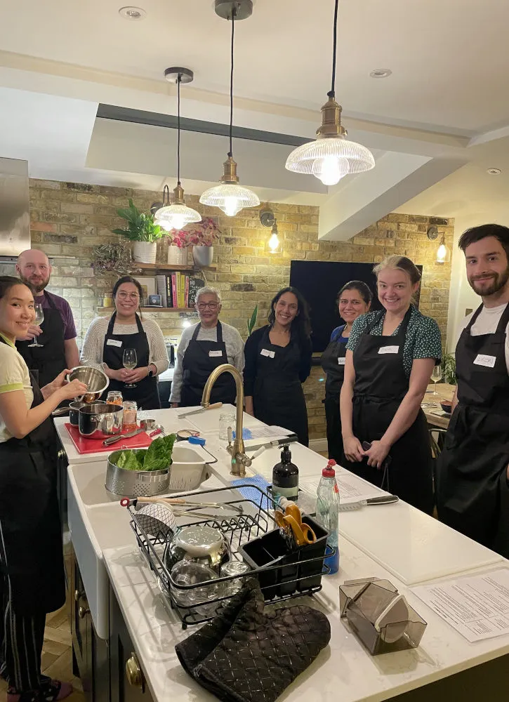 People standing around a kitchen island in a cooking class